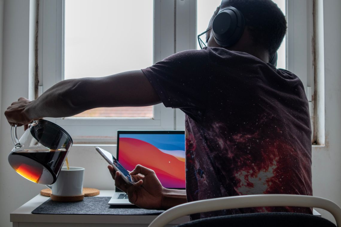 Man at desk pouring a cup of coffee