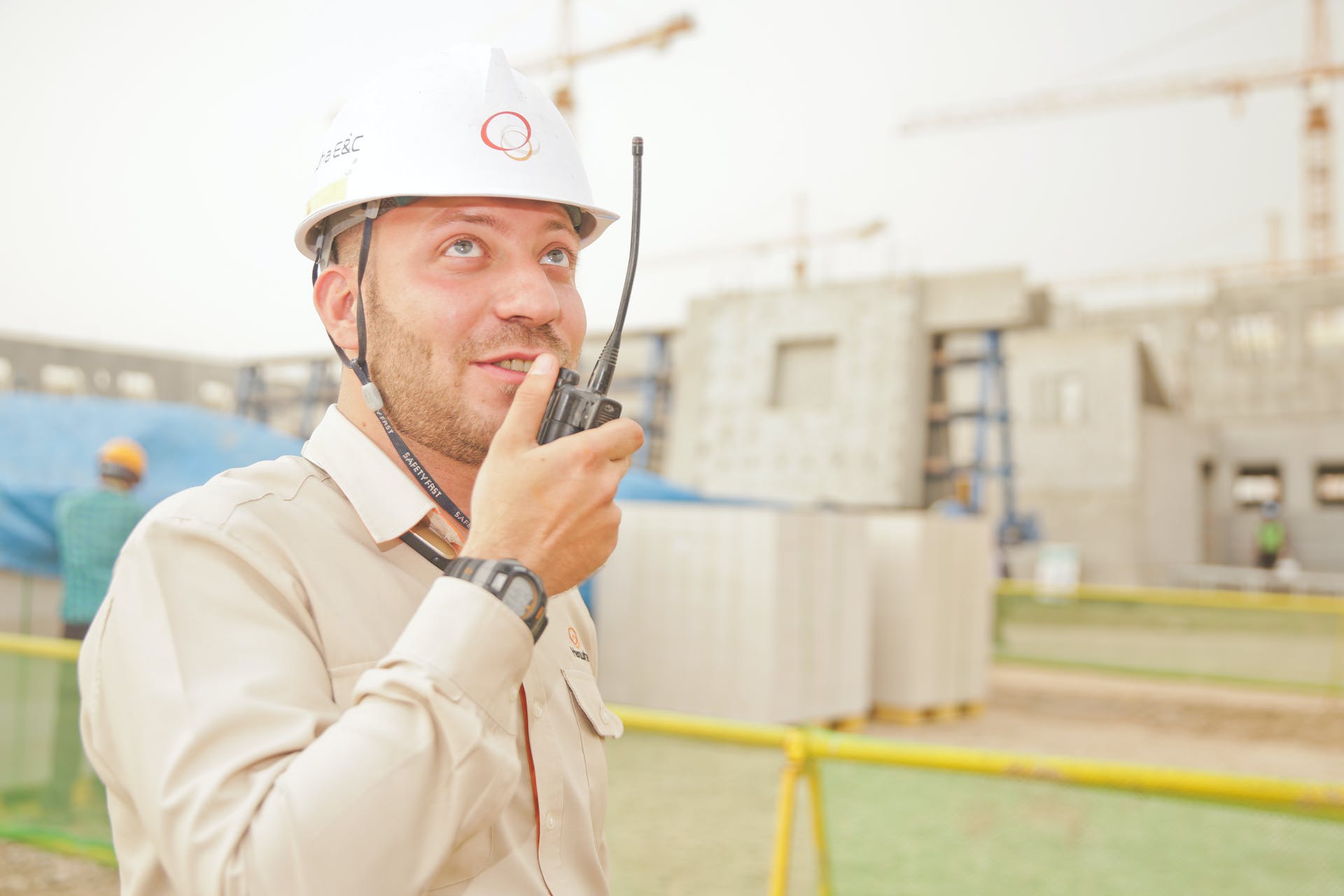 Construction site manager in a hard hat speaking into a radio