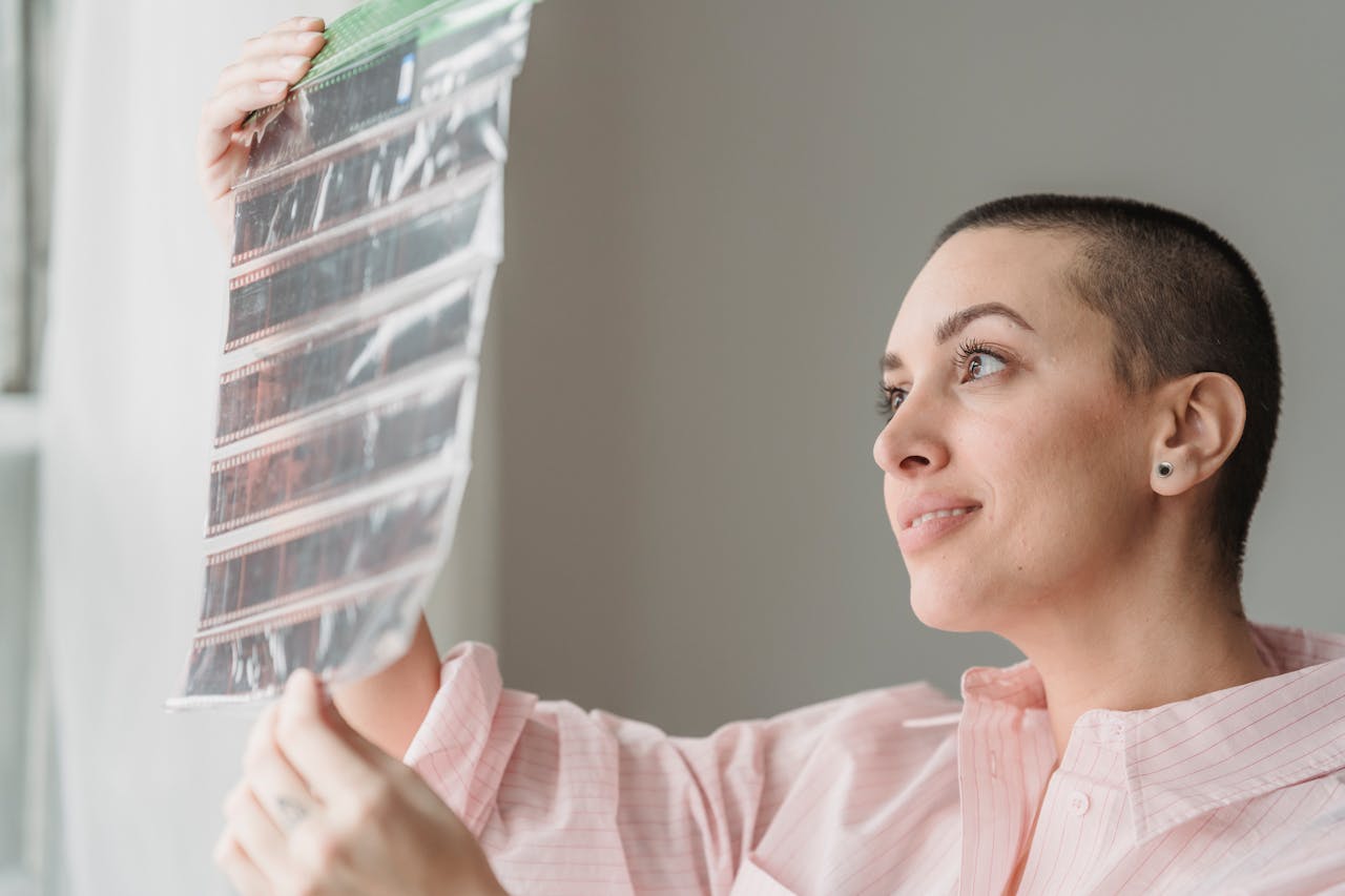 Smiling young woman checking images on negatives in light studio